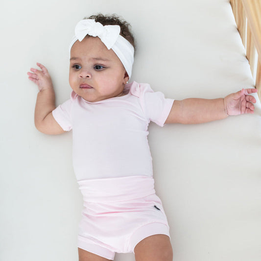 Infant wearing Kyte Baby Bummies shorts in Sakura