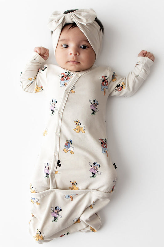 Baby in Mickey Mouse and Friends printed bundler with button closures and cream bow