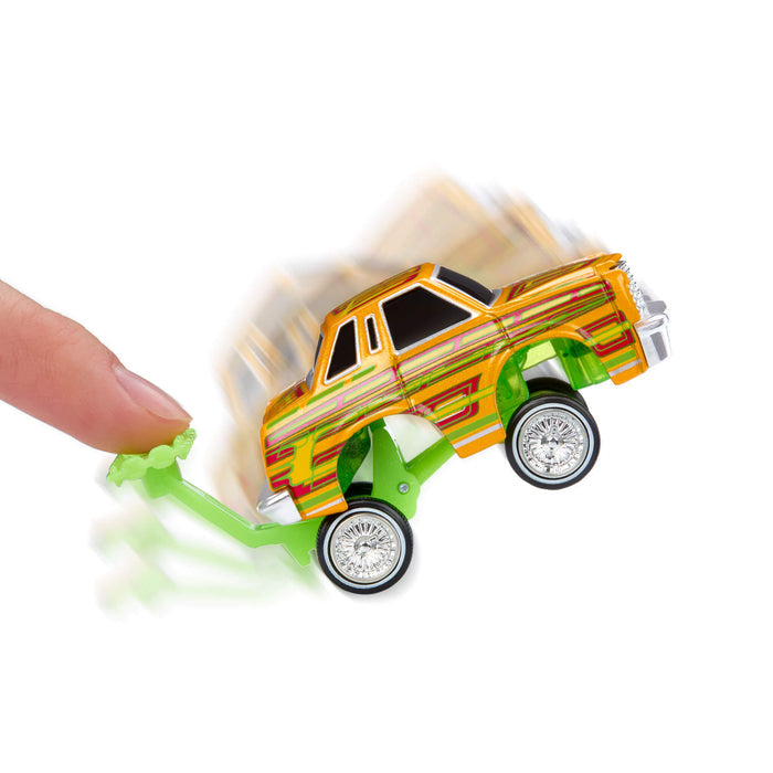 Toy car with a green base being pushed by a finger on a white background