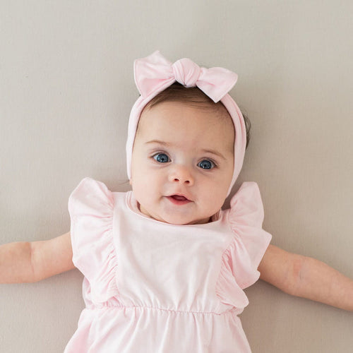 Infant wearing Kyte Baby Bow in Sakura Pink