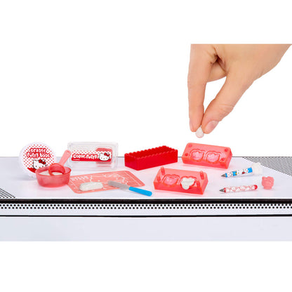 Set of small red and white items on a white surface with a hand reaching towards them.