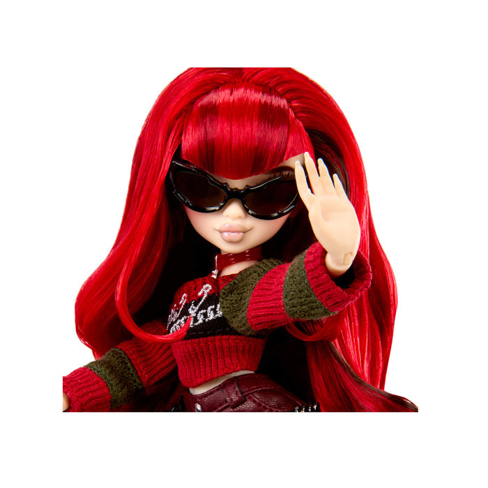 A doll with long bright red hair, wearing black sunglasses, a red and dark green striped knit sweater, posed against a plain white background.