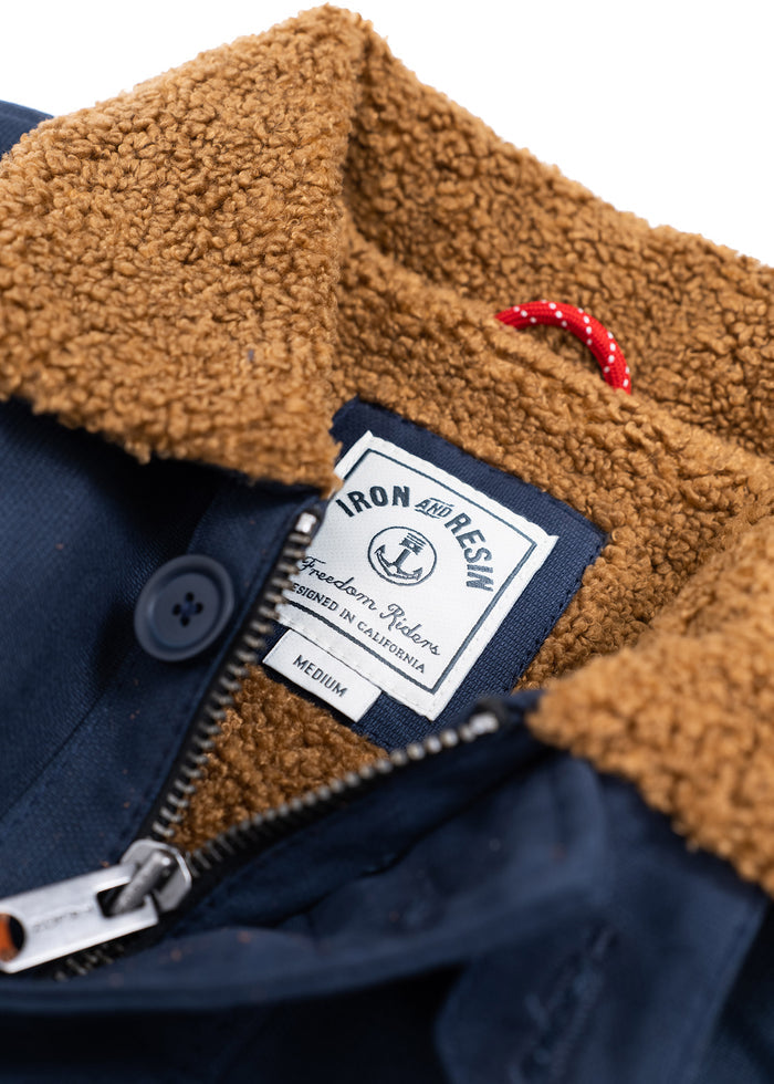 Navy jacket with brown sherpa collar, visible Iron and Resin label, medium size, designed in California, red loop detail.