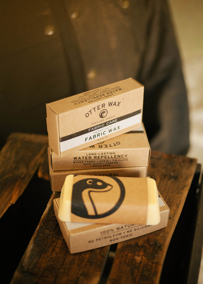 Otter Wax fabric care products on a wooden surface, featuring natural, water-repellent wax bars in eco-friendly packaging.