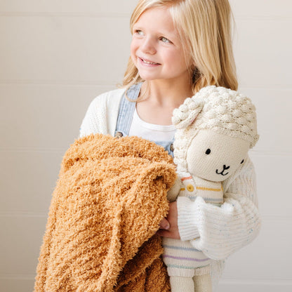 Smiling little girl holding stuffed lamb and extra soft Golden RIBBED BAMBONI TODDLER BLANKETS - Saranoni