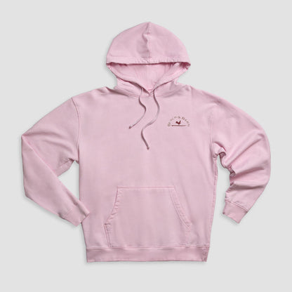 A light pink hooded sweatshirt with a front pocket and drawstrings, featuring a small logo with text and a bird graphic on the upper left chest. The hoodie is laid flat on a light gray background.