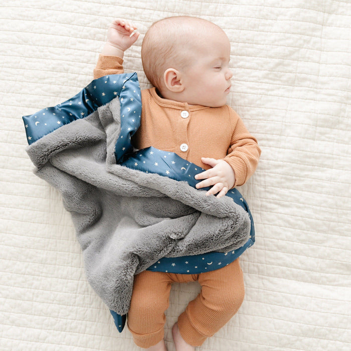 Baby sleeping wrapped in a starry night patterned satin mini blanket.