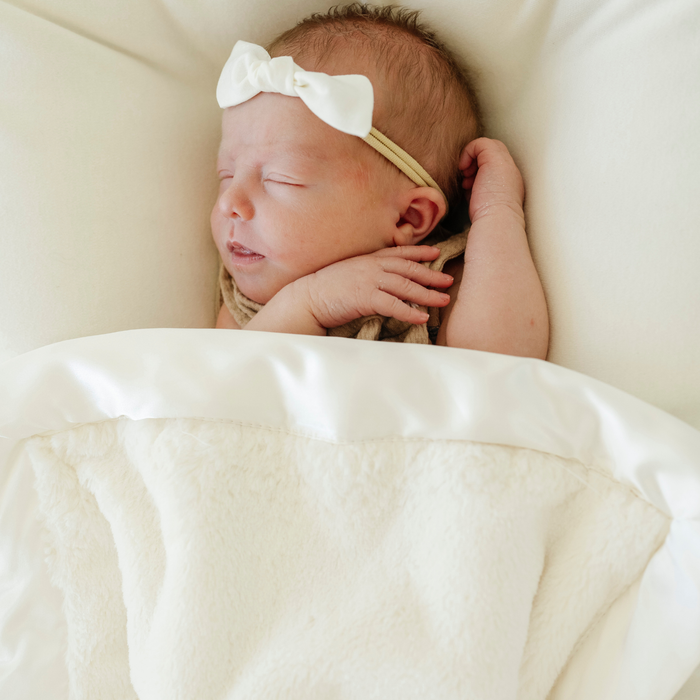 Baby girl with Saranoni satin mini baby blanket in Ivory.