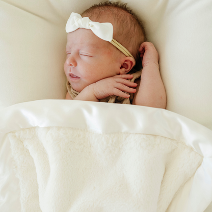 Baby girl with Saranoni satin mini baby blanket in Ivory.