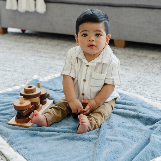 Boy playing on a blue receiving blanket.