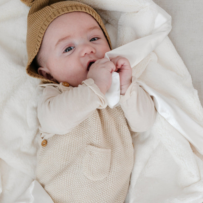Baby snuggling with a soothing and soft white receiving blanket.