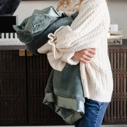 Little girl snuggling tight with a deep green toddler sized blanket.