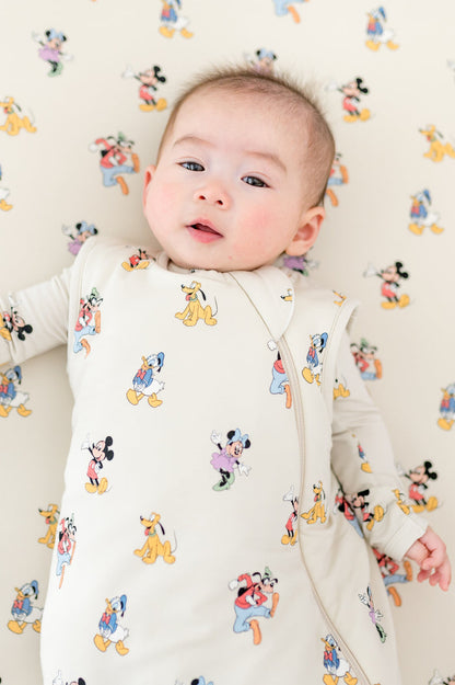 Baby wearing a sleep sack with cartoon character patterns on a matching background