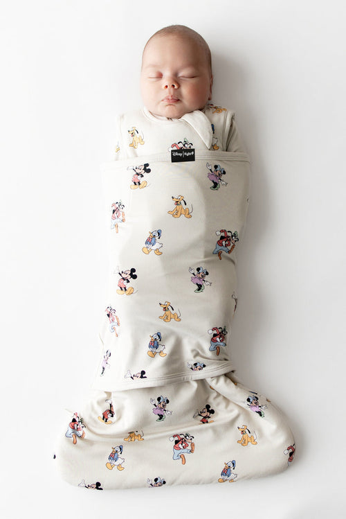 Baby asleep in kyte baby sleep bag swaddler with mickey and friends pattern