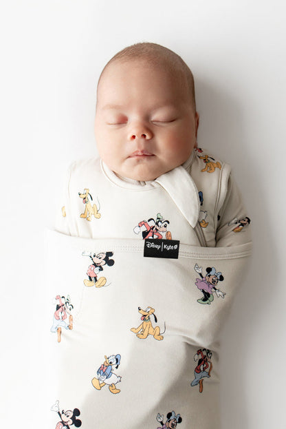 Baby sleeping in a Disney-themed baby swaddle on a white background