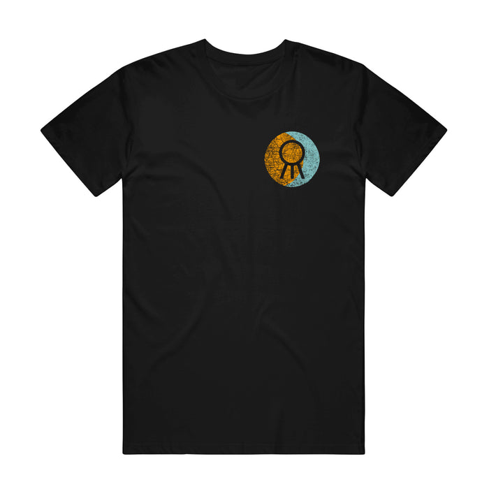 A black Hail The Sun Comfort Colors t-shirt with a small circular left-chest design: half orange, half blue, and a black ribbon icon in the center—a subtle nod to the band.