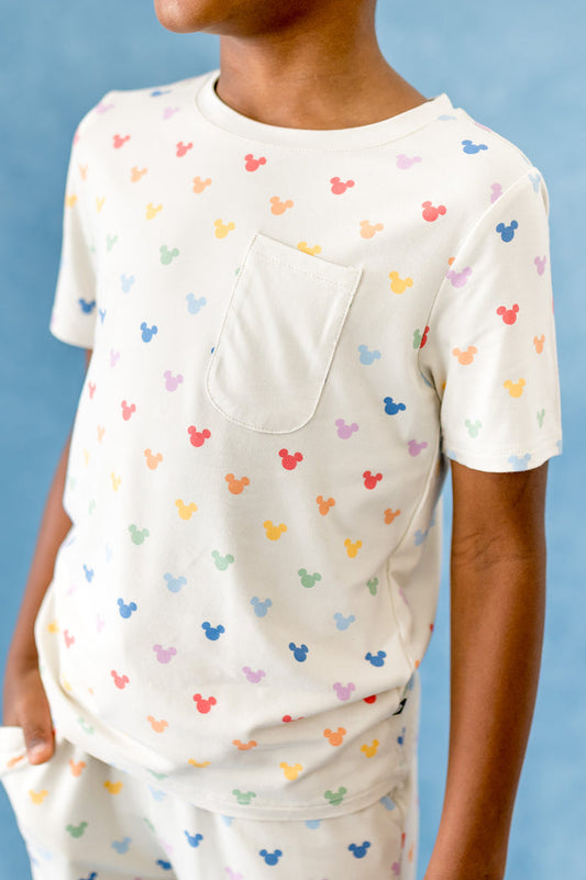 Child wearing a white t-shirt with colorful mouse ears pattern against a blue background