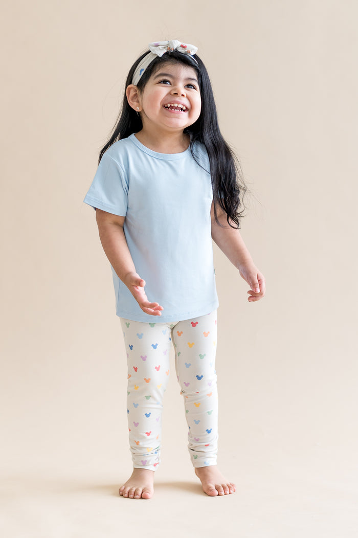 child wearing a blue tshirt with mickey mouse head patterned leggings