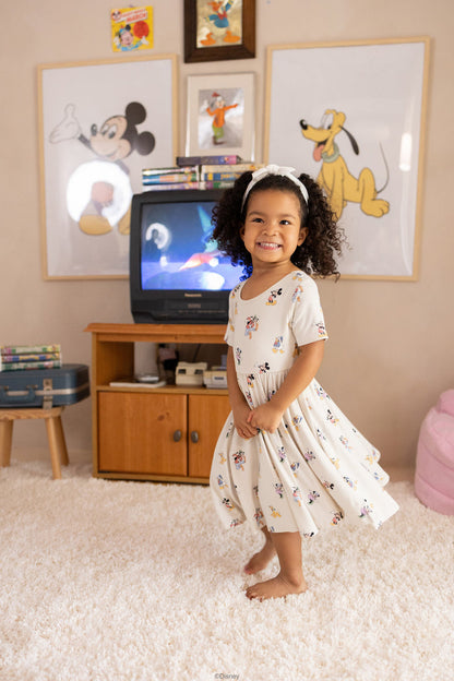 Child in a room with Disney-themed decor, including a television and framed pictures of cartoon characters.