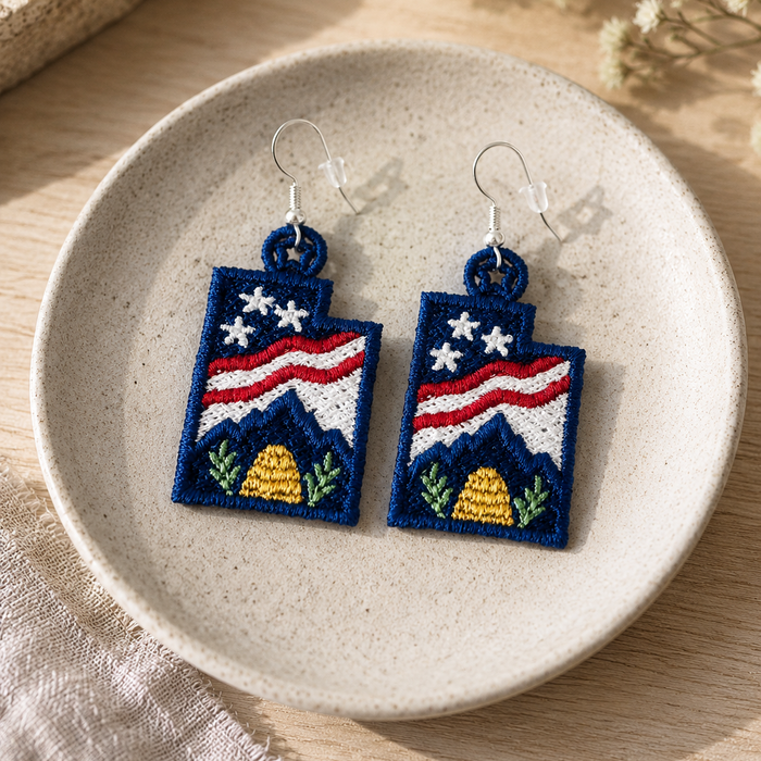 Embroidered earrings with American flag design on a ceramic plate.