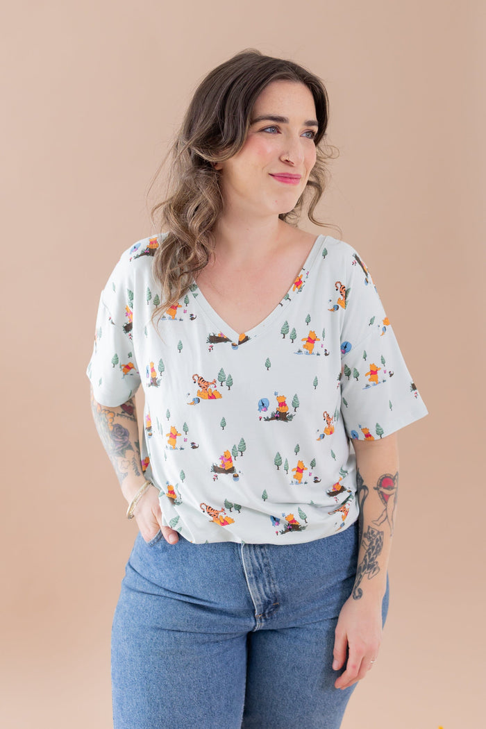 Female modeling the  Women's Relaxed Fit V-Neck in Winnie the Pooh Hundred Acre Wood paired with medium wash jeans