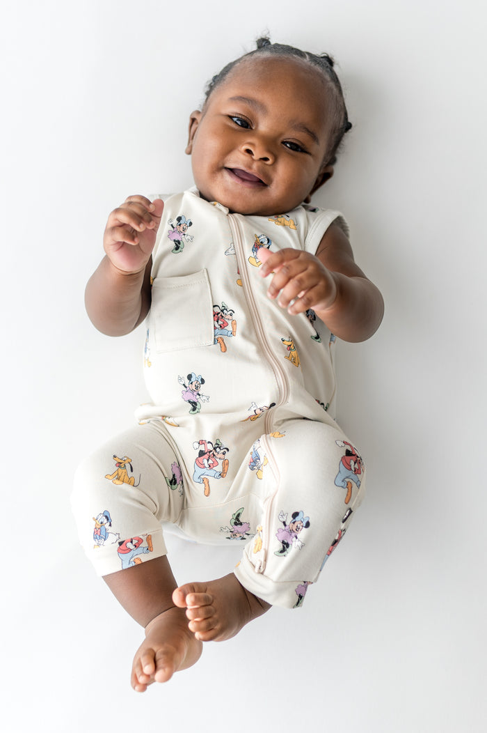 Baby in a sleeveless zippered romper with a mickey cartoon pattern